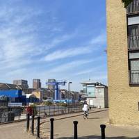 With the Thames on your left, walk around the riverside path to the entrance of South Dock.